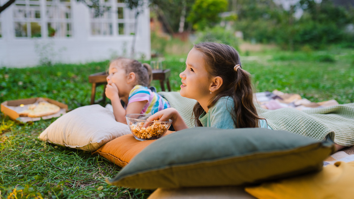 Young girls watching movie in their backyard