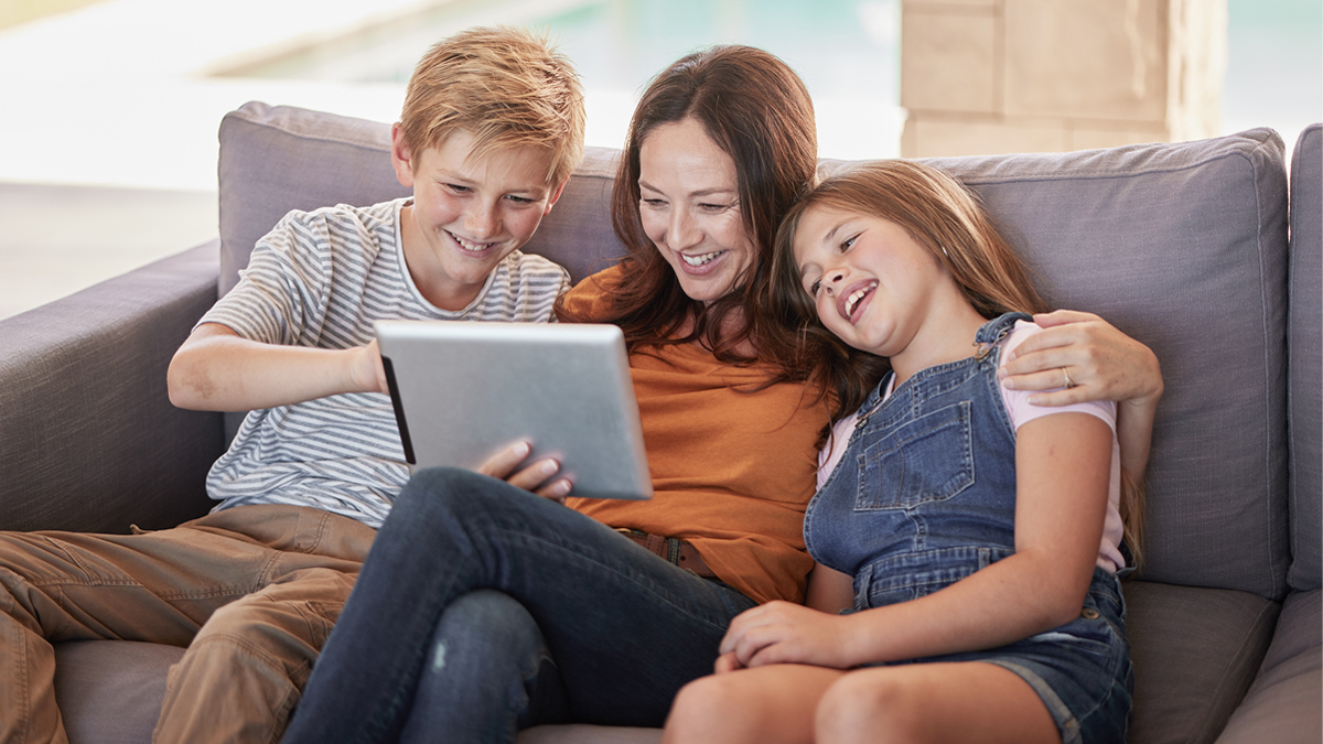 Two kids looking at screen with mom on couch