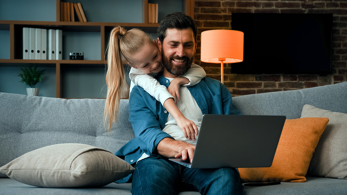 Dad and daughter looking at screen together in living room
