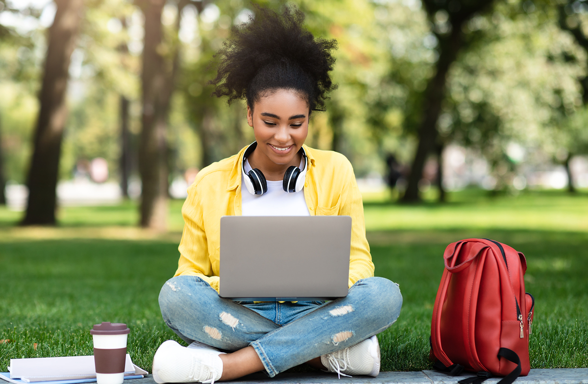 High school student studies on laptop in park