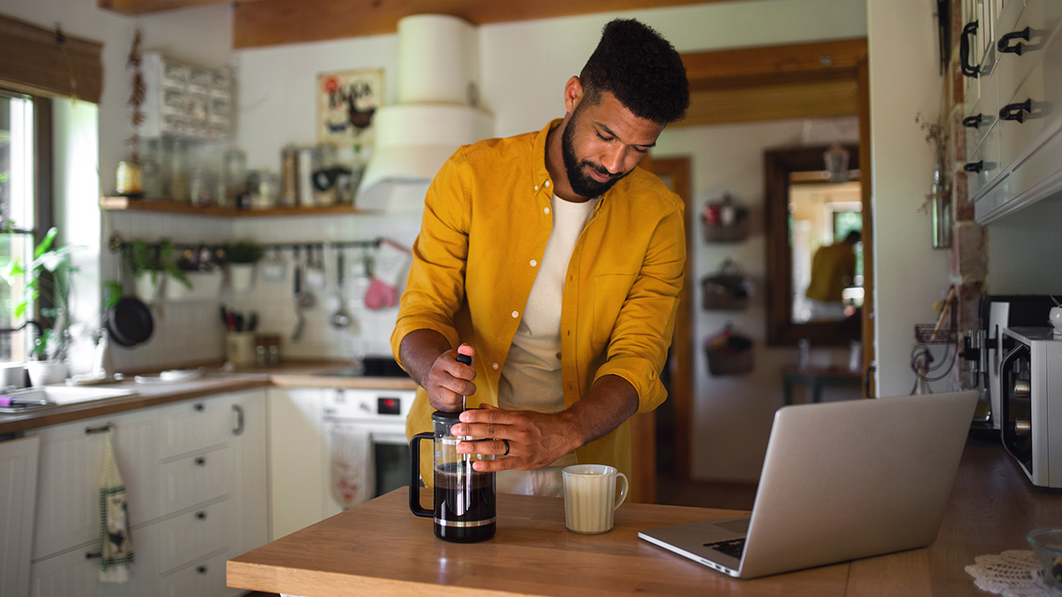 Man using french press to make coffee in kitchen