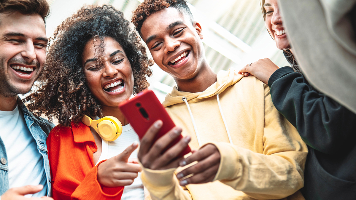 Group of young adults laughing at phone screen