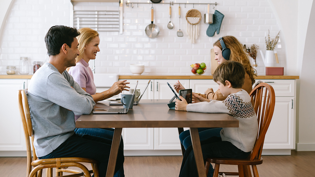 Family on devices together at kitchen table
