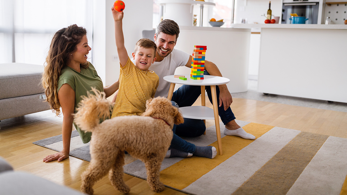 Young family playing with little dog and colorful Jenga game