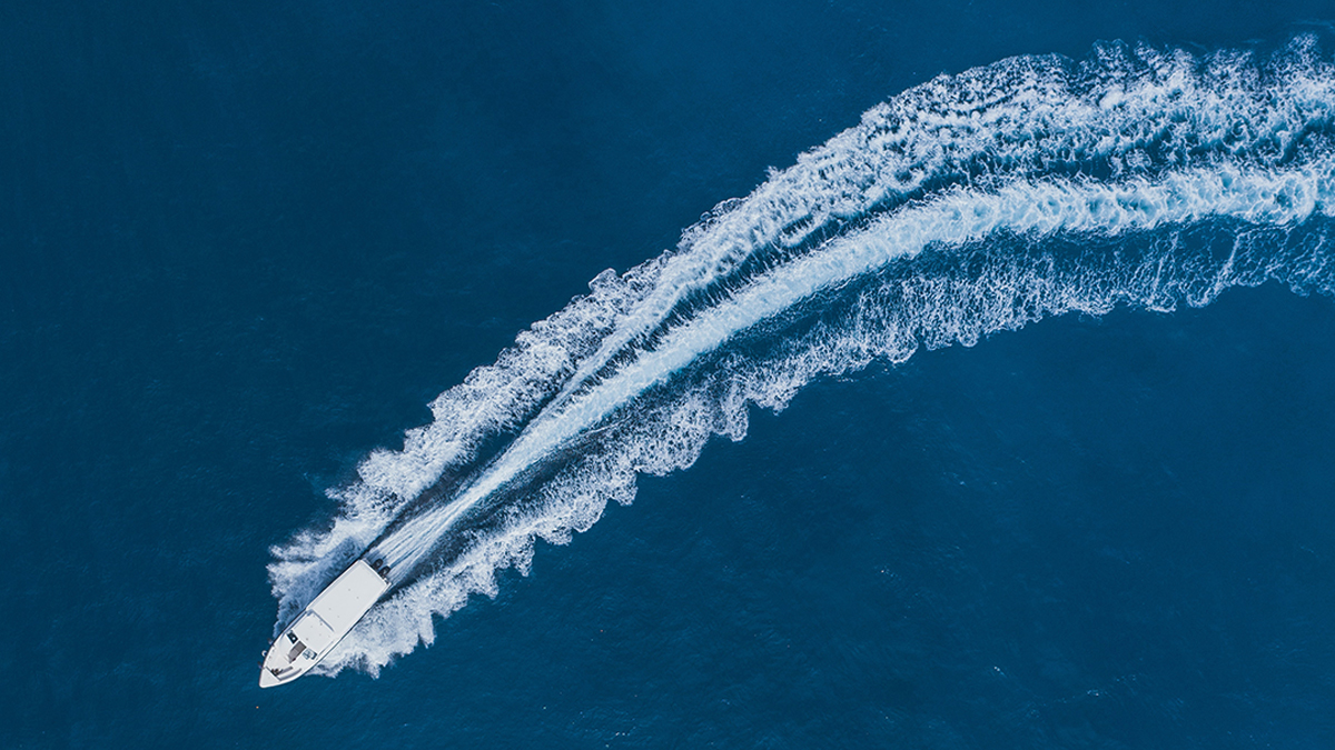 Speed boat leaving a foamy wake through deep blue sea
