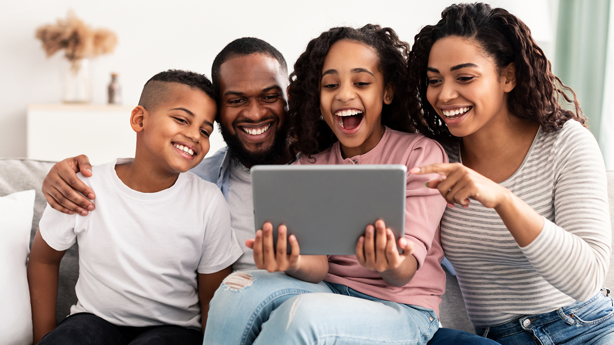Young family laughing at digital tablet together