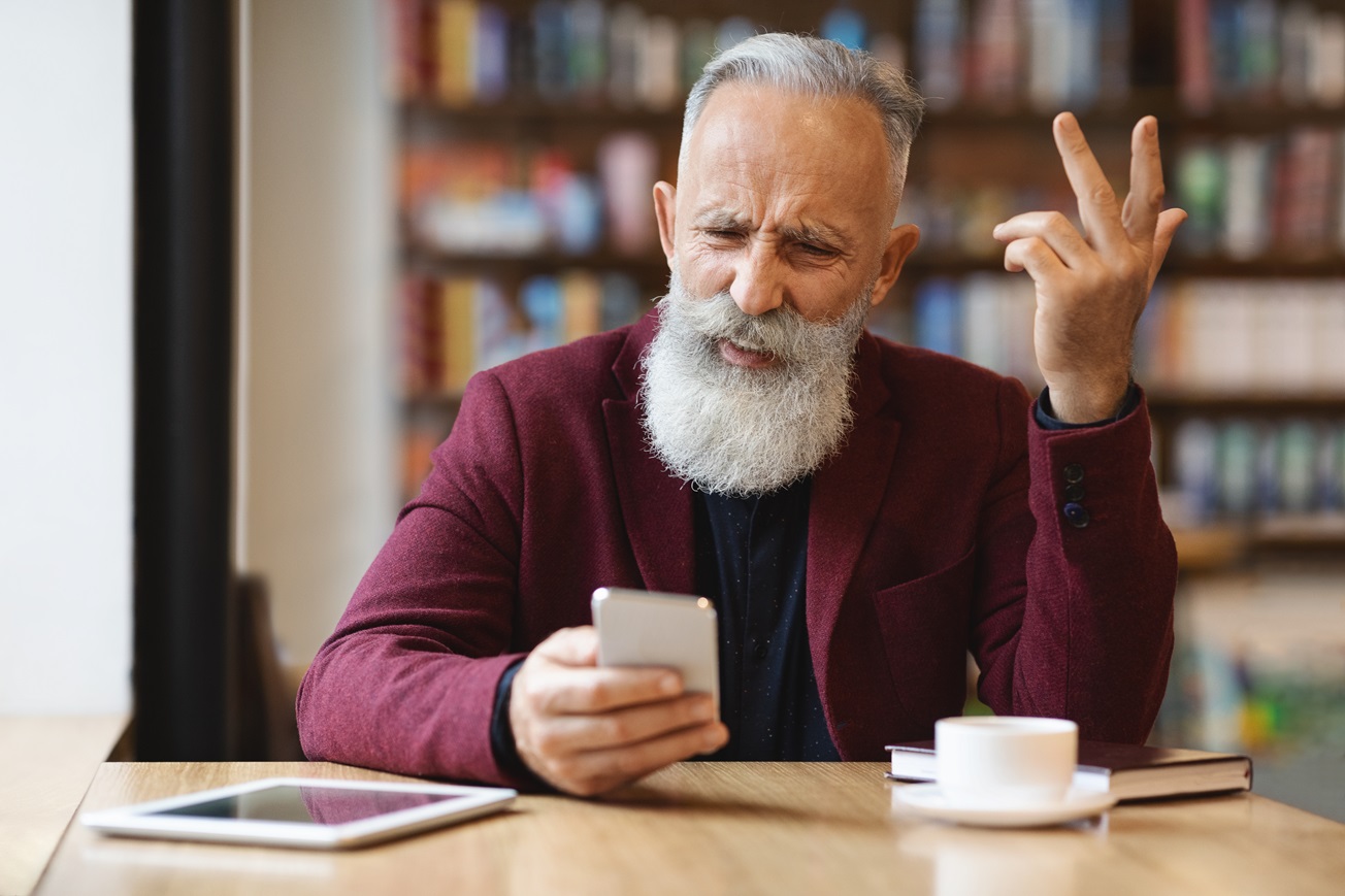 angry senior man using mobile phone at cafe 2023 11 27 05 08 19 utc
