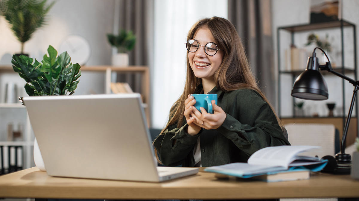 Young woman on computer and holding coffee mug