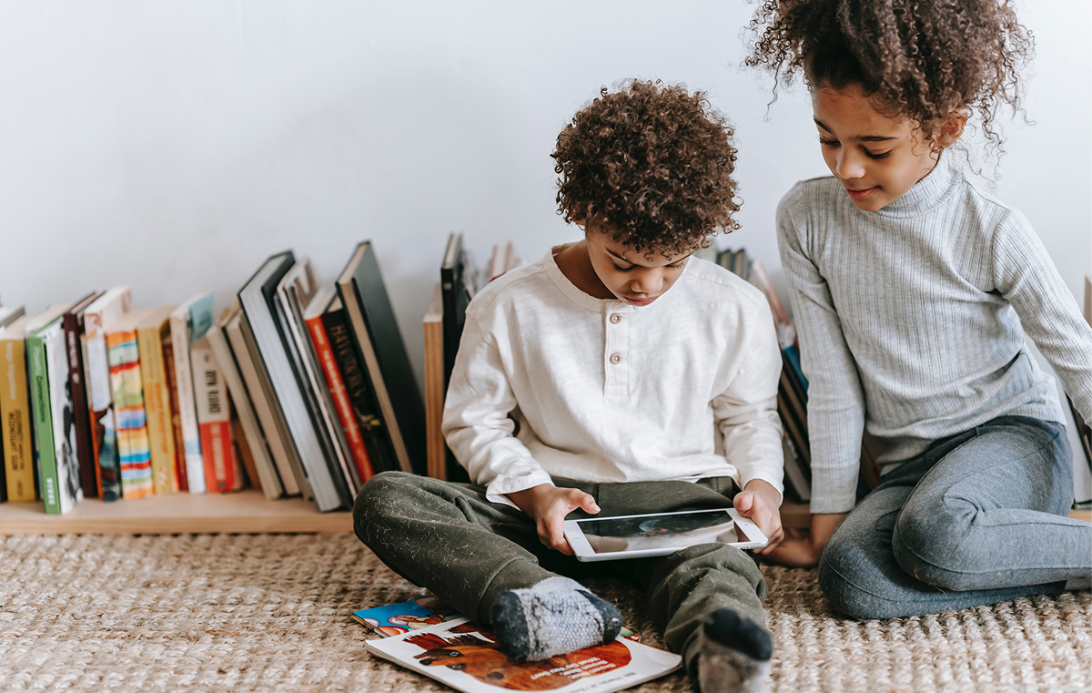 Little boy and older sister reading on digital screen together