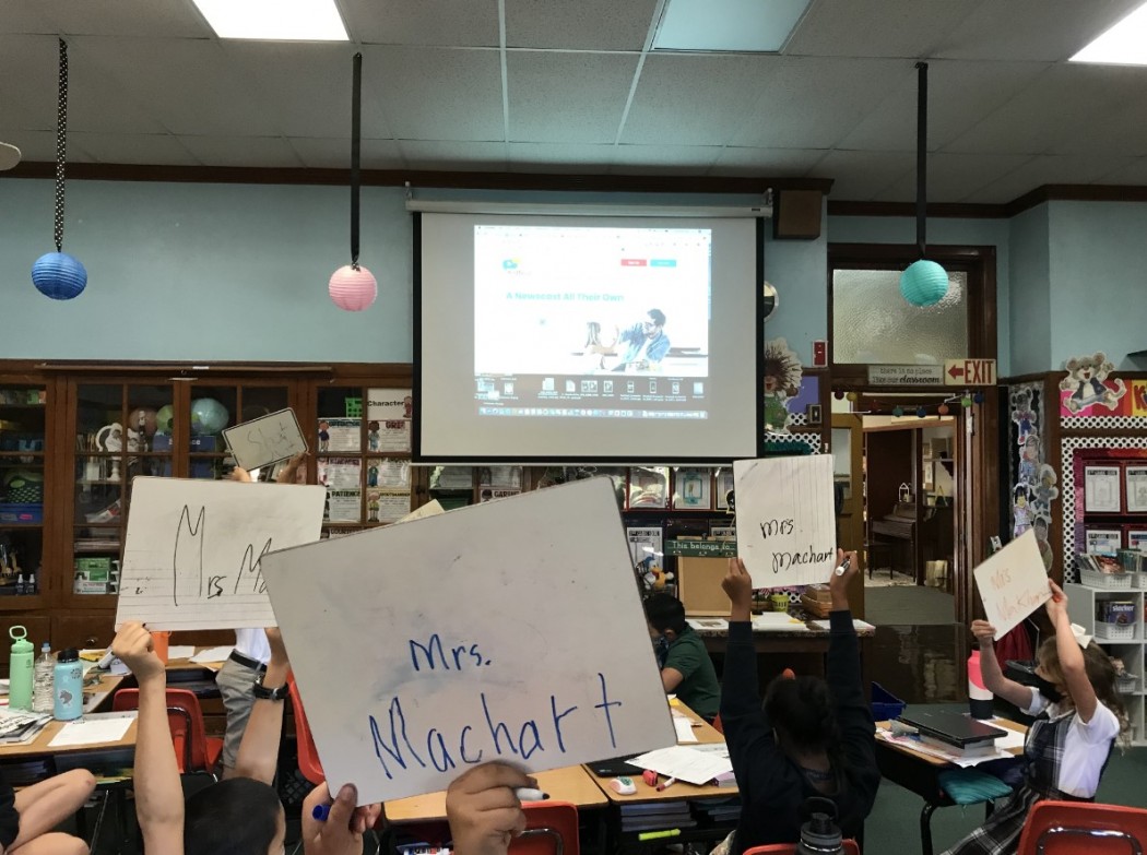 Classroom of children holding signs with teacher's name