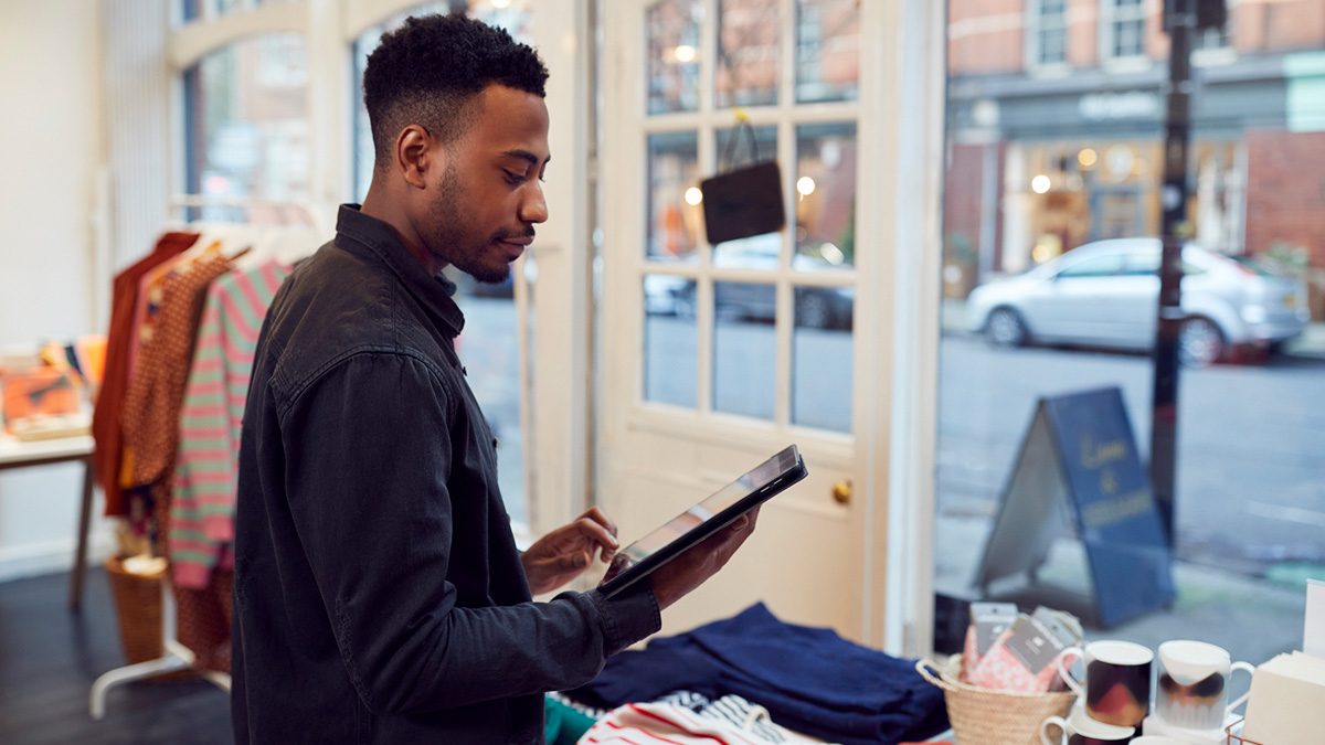 Man on tablet in small business downtown