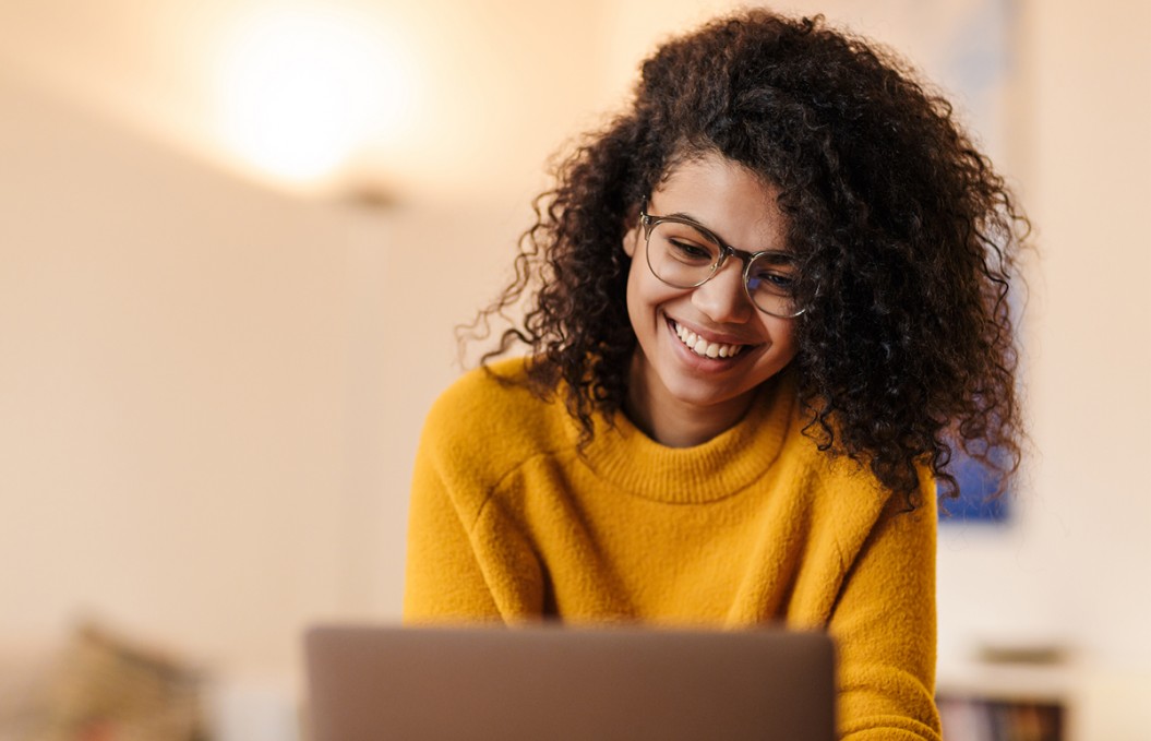 Woman with glasses smiling at laptop