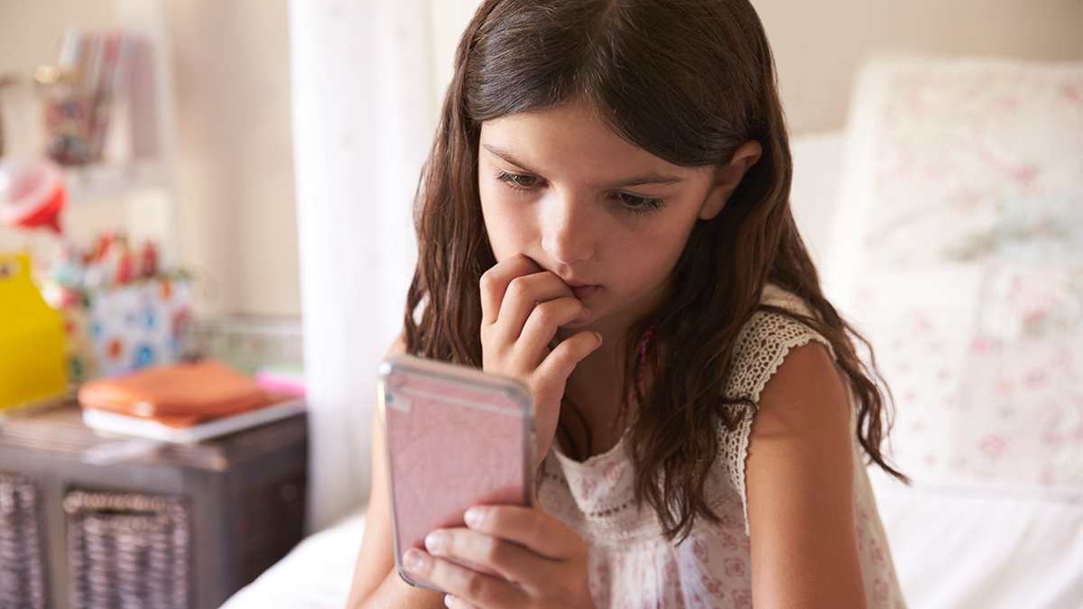 Anxious little girl looking at phone screen