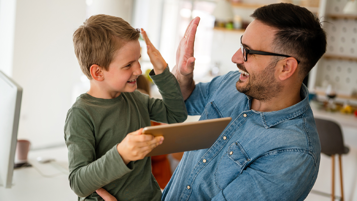 Father and son on digital tablet and giving each other a high five