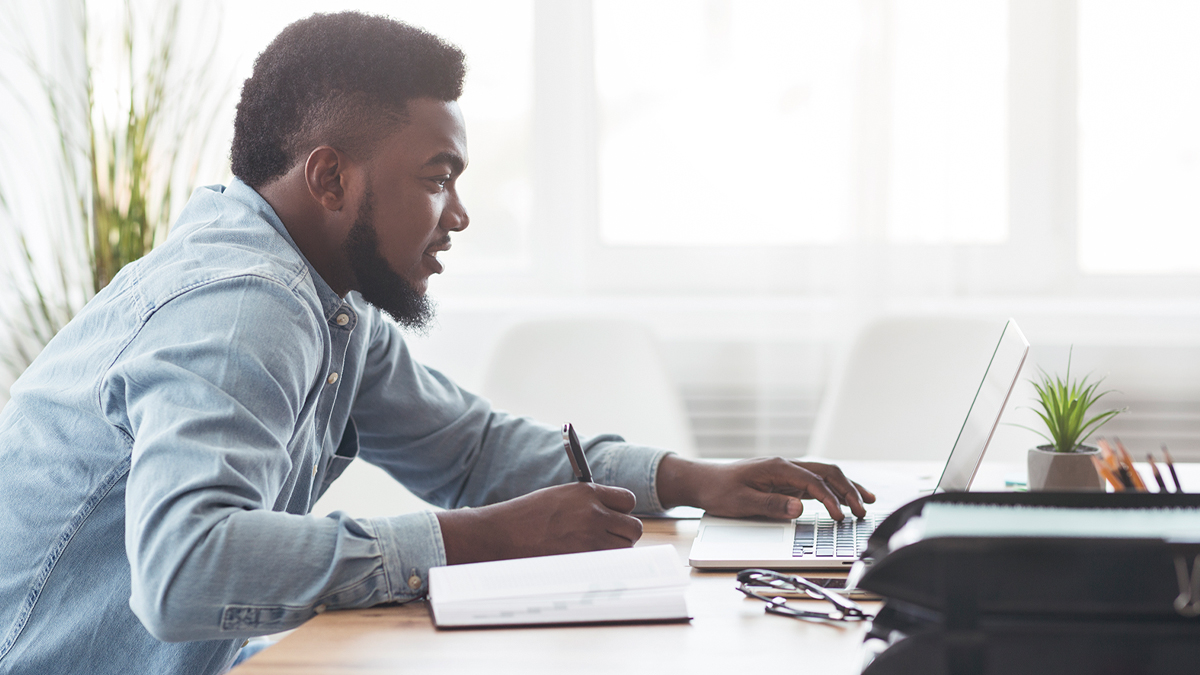 Man taking notes as he read computer