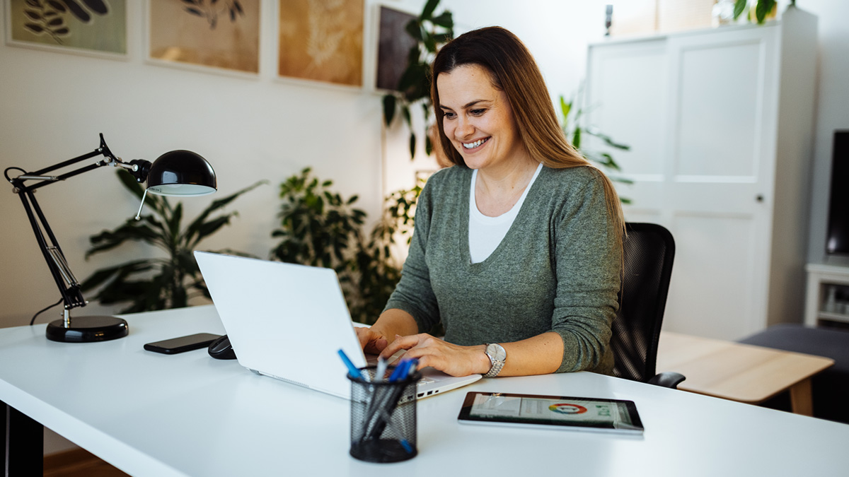 Woman smiling at laptop in her cozy home office