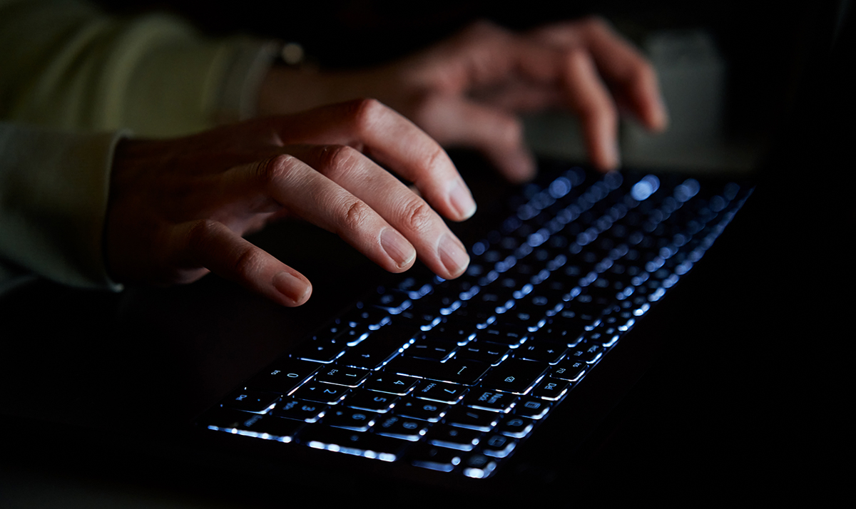 Hands typing on keyboard at night