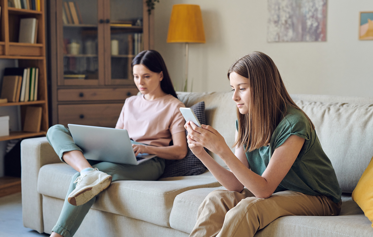 Teenager texting while mom is on laptop