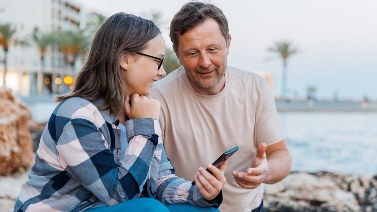 Dad explaining something to daughter holding phone