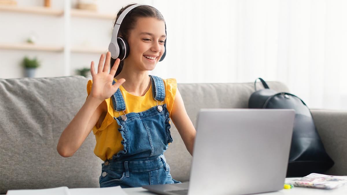 Young student waving to teacher on computer