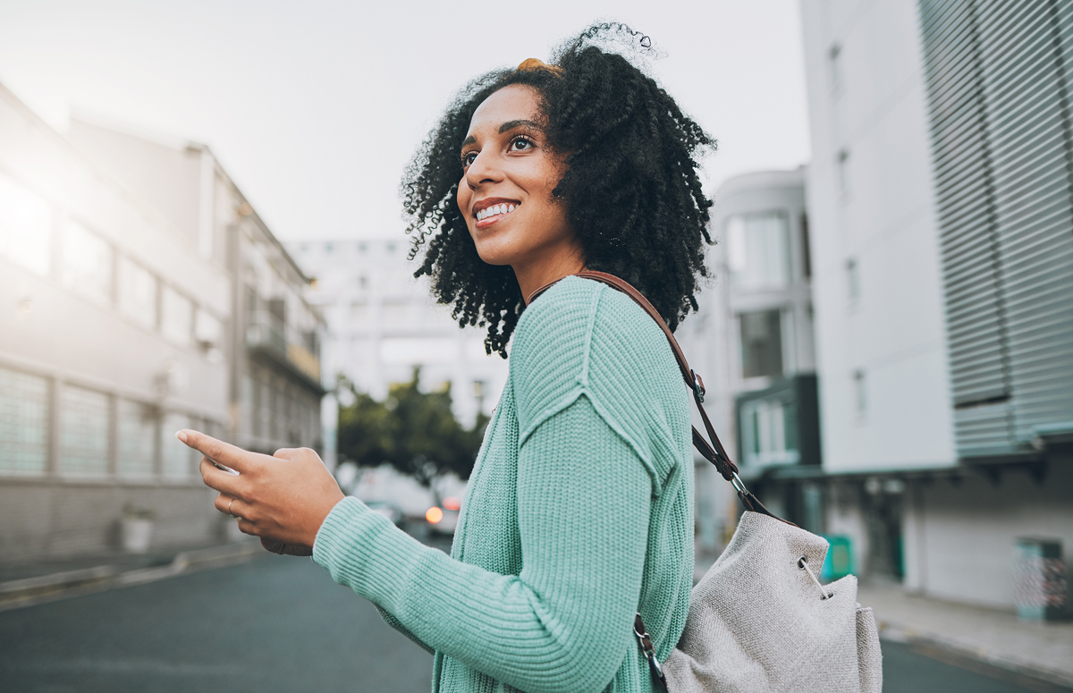 Woman traveling with backpack in urban area, using phone to navigate