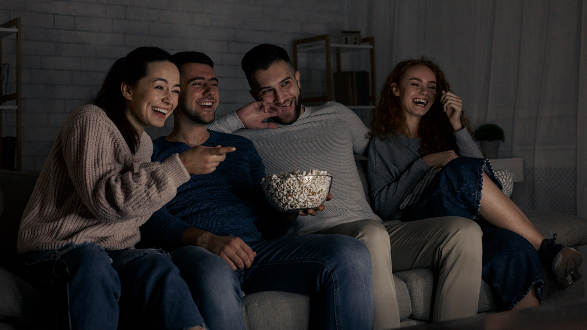 Group of friends laughing as they watch TV