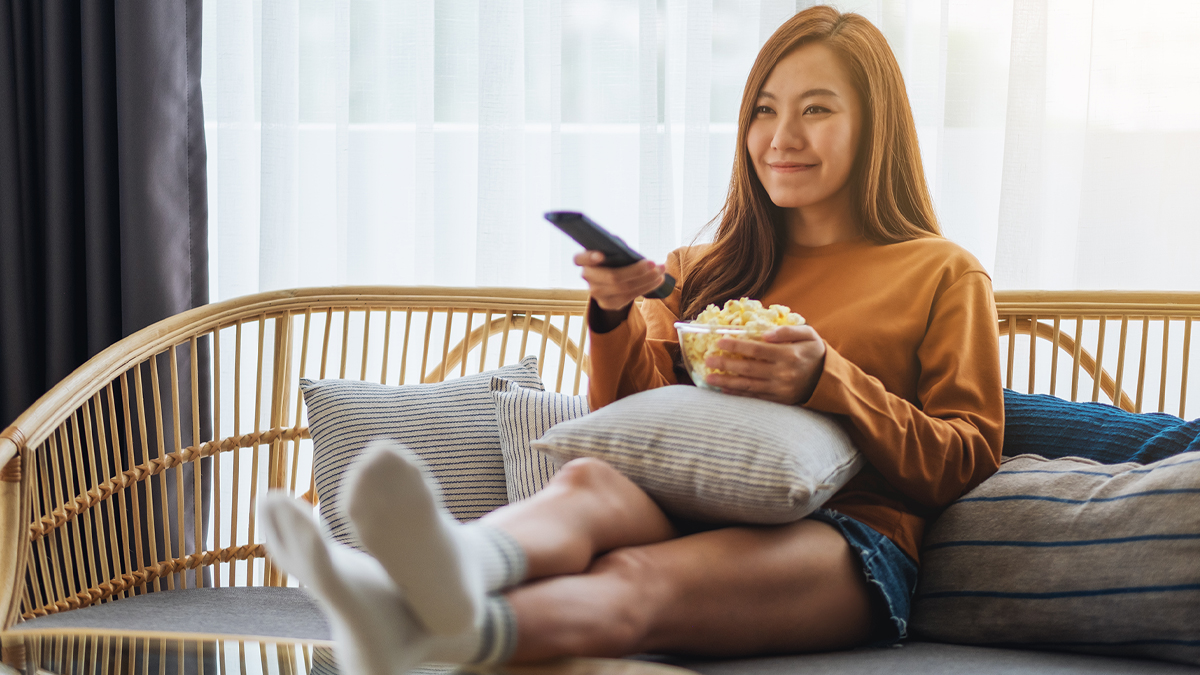 Young woman pointing remote at TV