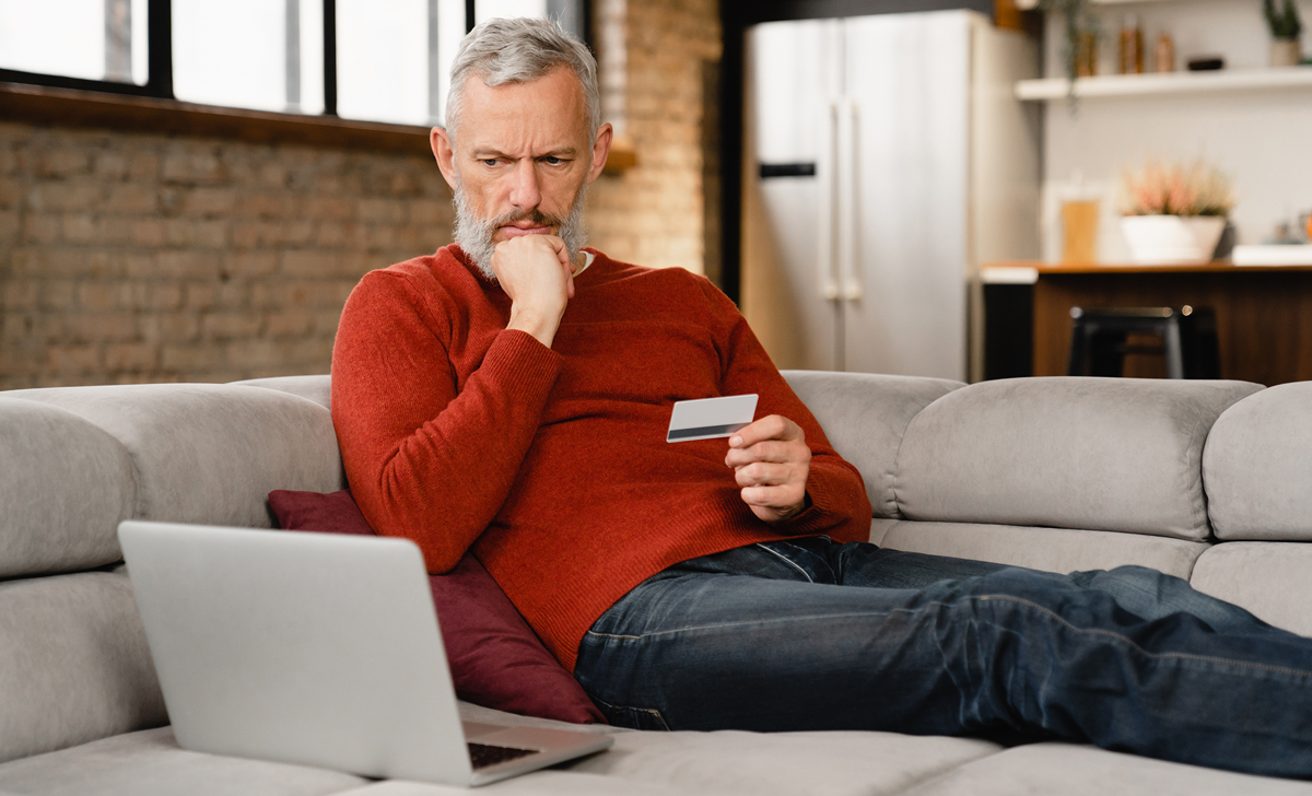 Man looking at computer scam and credit card suspiciously