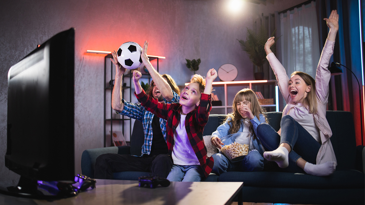 Parents and two children watching sports game and celebrating a win