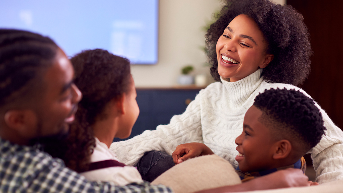 Family laughing together as they watch TV